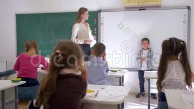 在教室里和老师一起坐在黑板旁听同学讲课的同学